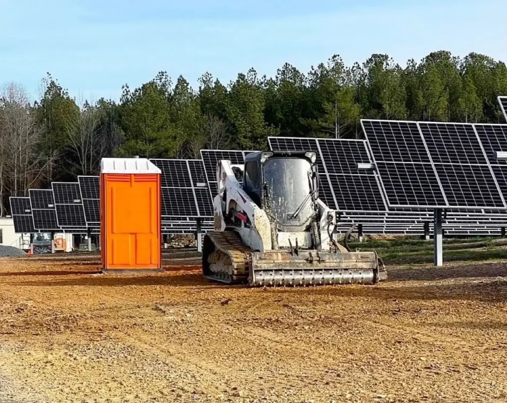 A construction vehicle with solar panels and trees in the background.