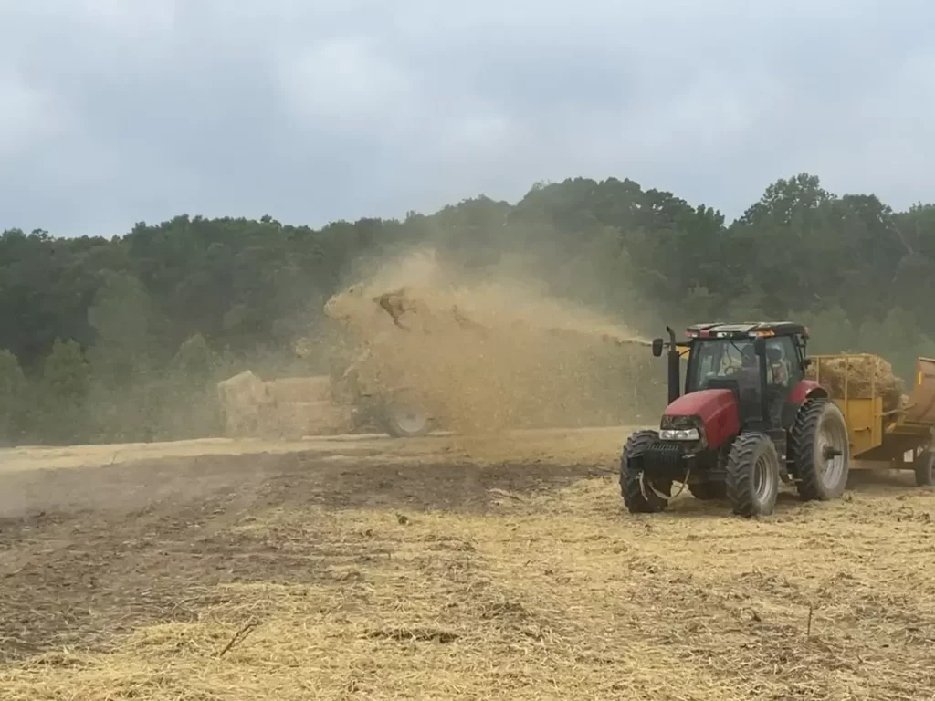 Tractor blowing straw mulch across a graded construction site