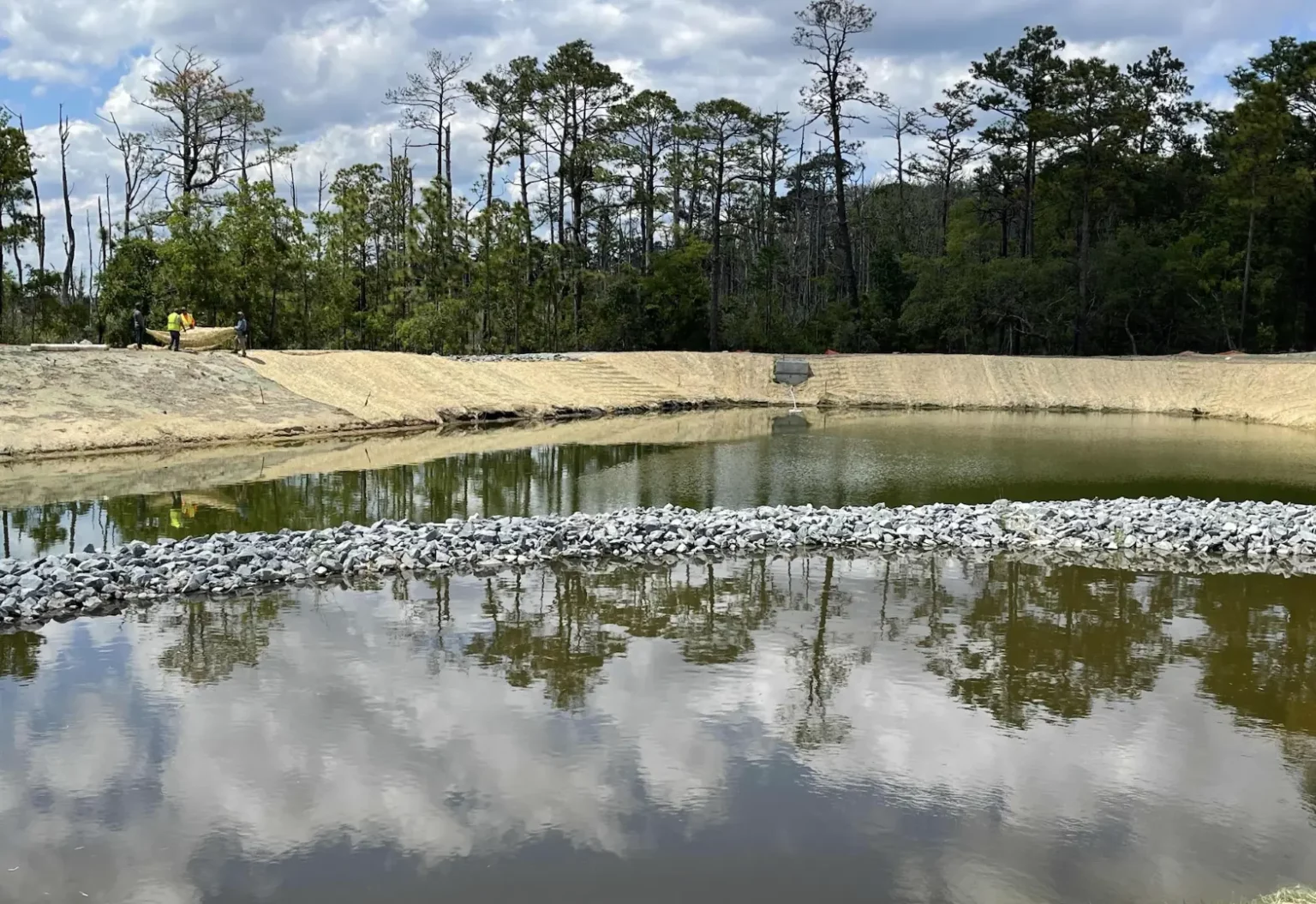 Installation of erosion control matting around the pond to stabilize slopes, protect soil, and support long-term vegetation growth.