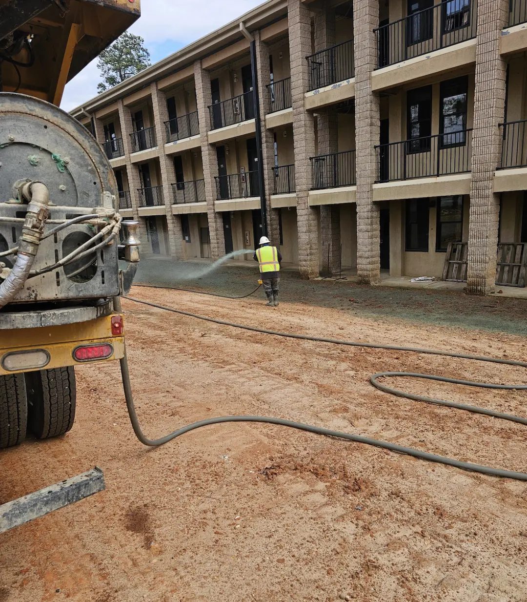 Hydroseeding around barracks for long term stabilization with hose attached to Epic Hydroseeder.